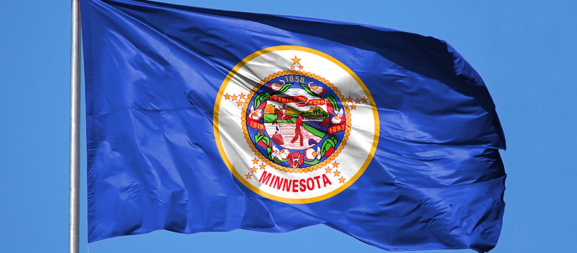 National flag State of Minnesota on a flagpole in front of blue sky.
